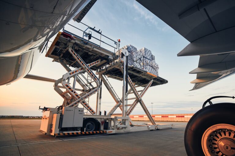 Loading of cargo containers to airplane at sunset