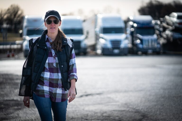 Woman truck driver walking in trucking yard while working in blue collar job